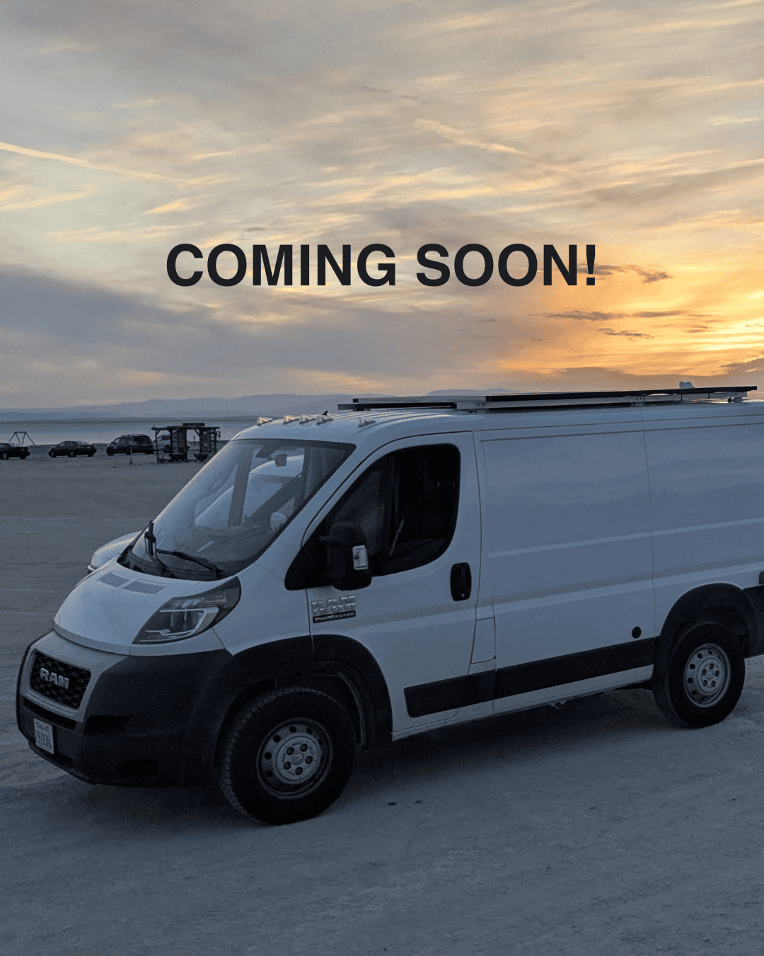 White Promaster low-roof campervan with solar panels on the beach under a stunning sunset