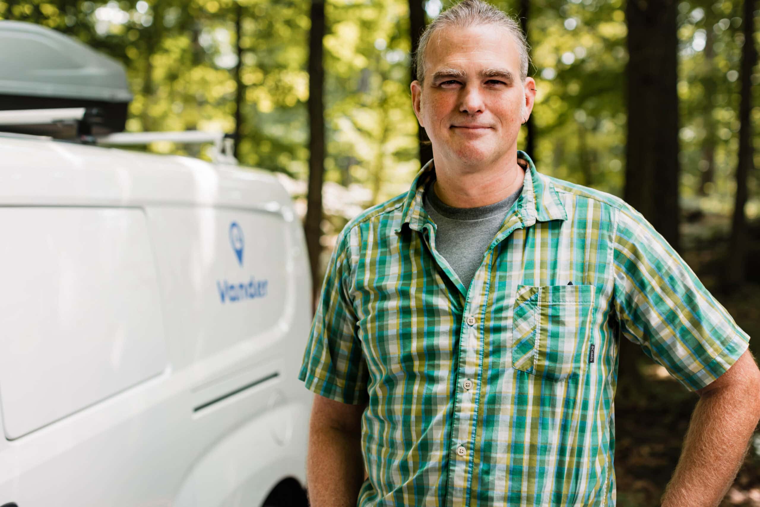 Vander owner in forest next to a compact campervan