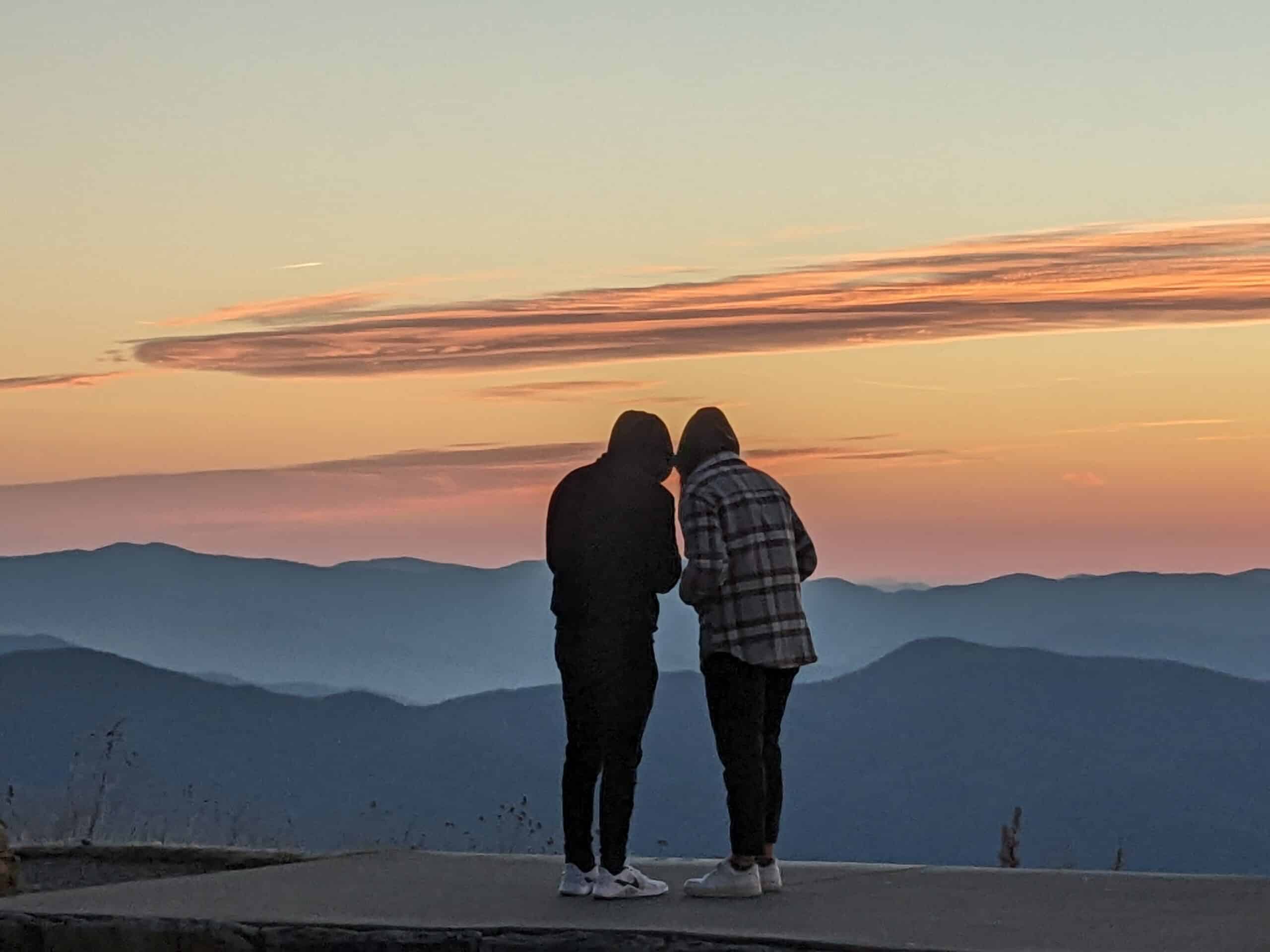 Two people sharing a sunrise over the blue ridge mountains