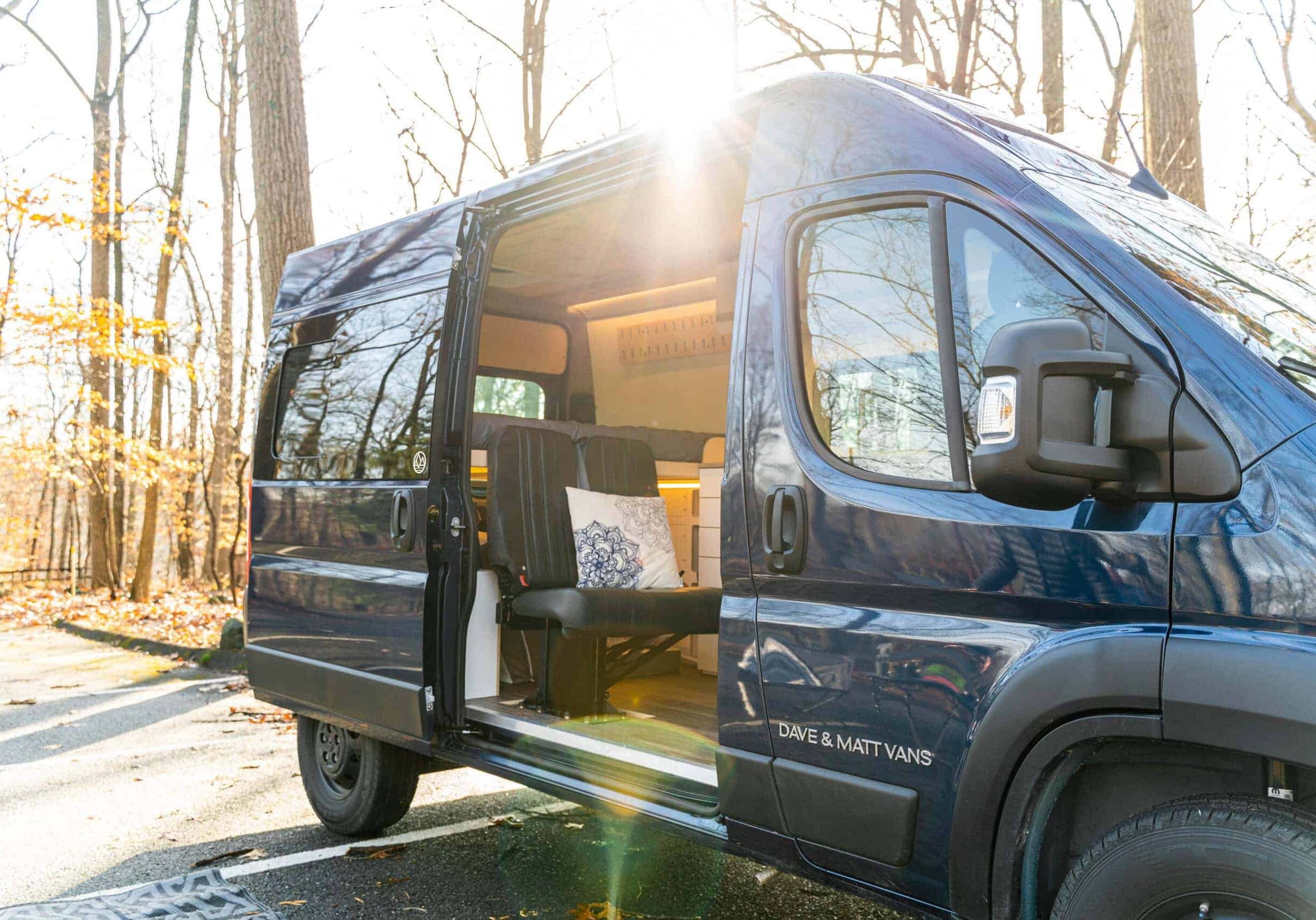 High roof blue campervan camping in an autumnal campsite.